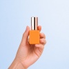 hand-holding-orange-pe-nail-polish-bottle.jpg